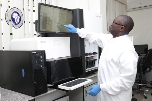 Christian Happi points to a screen on a sequencing machine in a lab at ACEGID.